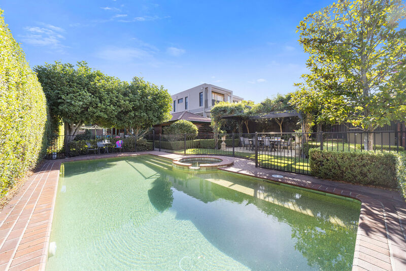 The pool and a garden conservatory seen across the rear lawn, showing the depth of the grounds