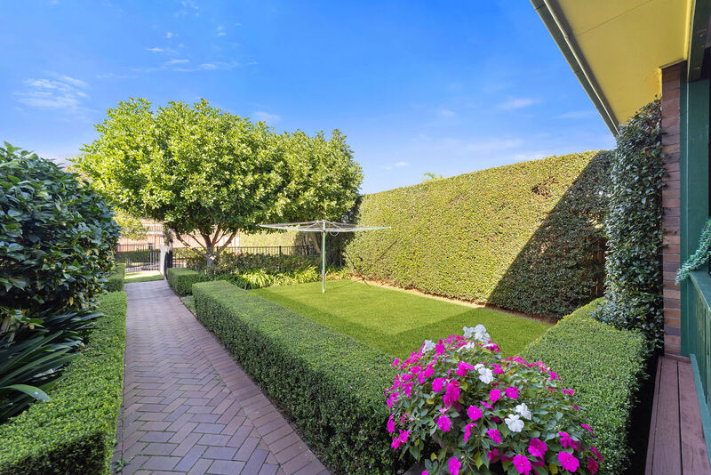 Landscaped gardens with clipped hedges, a brick path and a flowering border