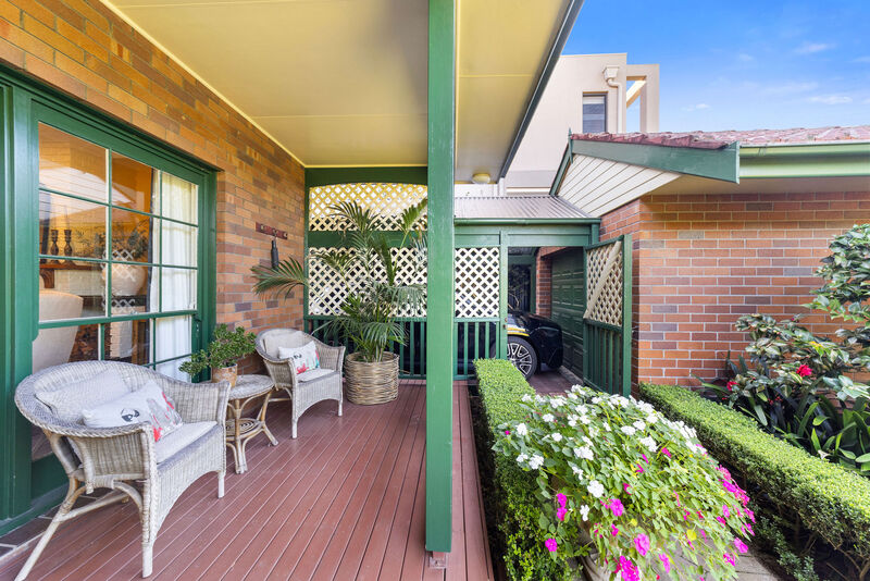 A covered verandah with outdoor seating opening onto the garden