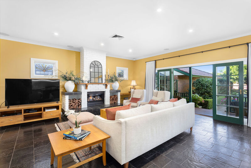 Open-plan living room with white sofas and glass doors opening to the garden