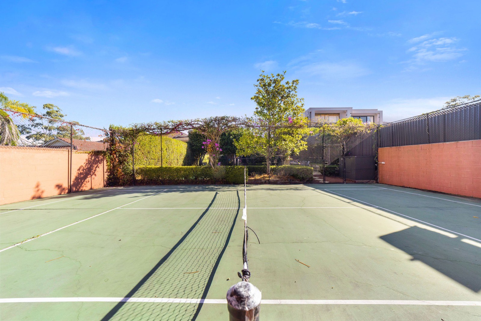 The private tennis court behind the home